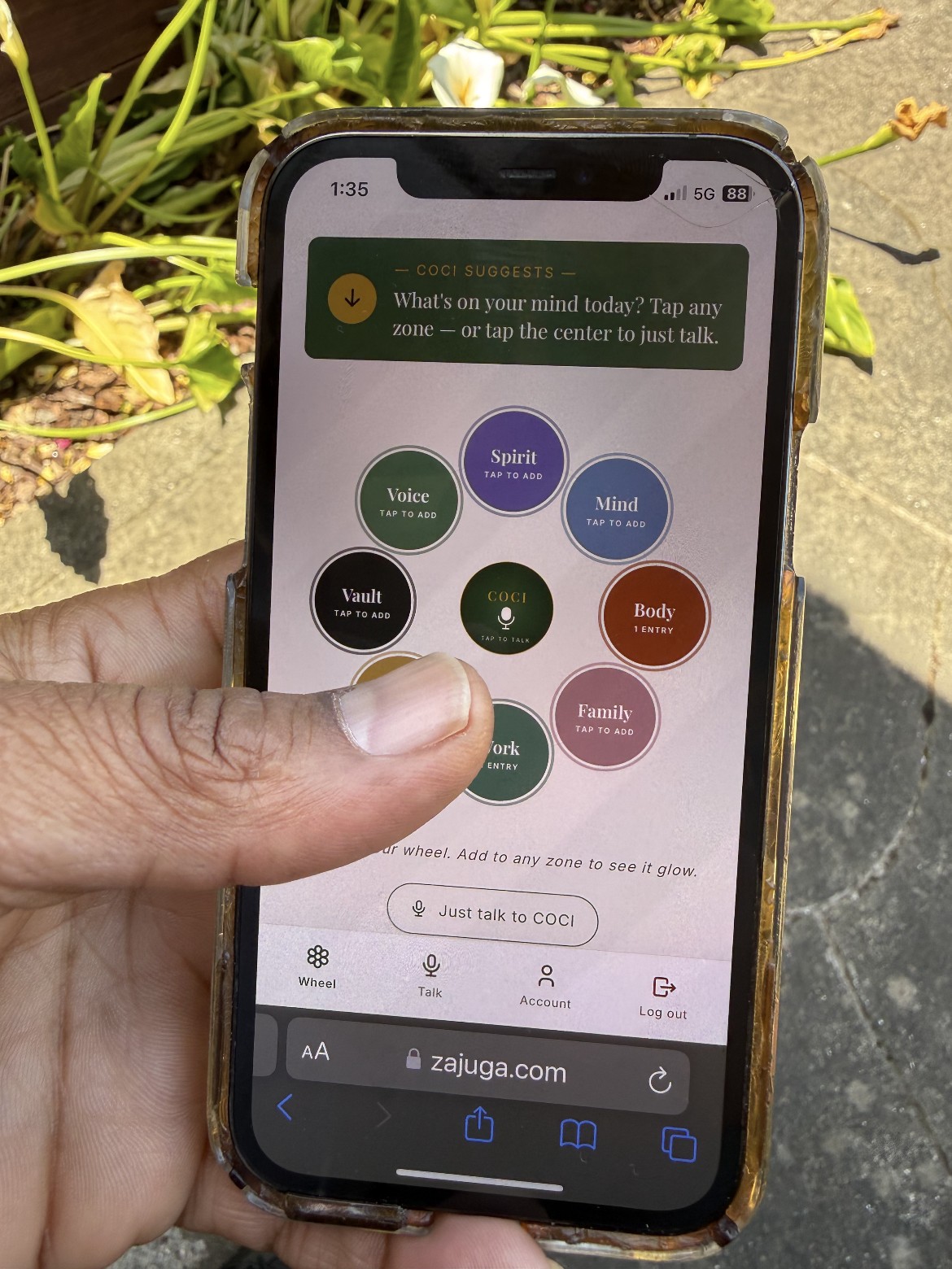 A hand holding a phone showing the COCI dashboard in use