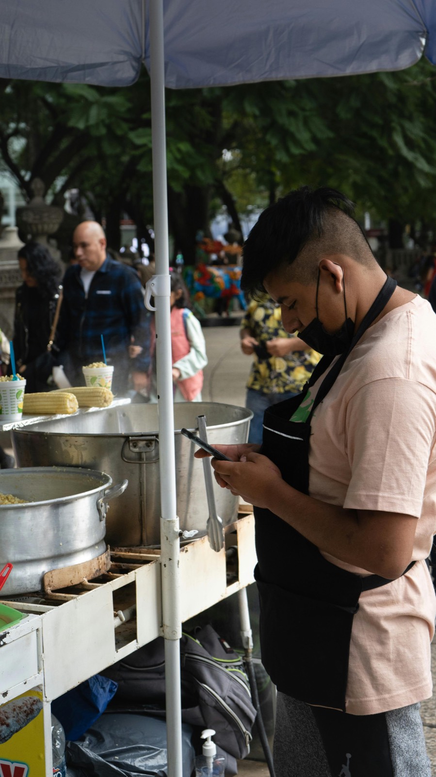 Mexican street food vendor on his phone between customers